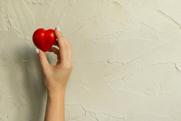Ripe tomato in the shape of a heart in hands. Healthy food on grey concrete background. Funny,...