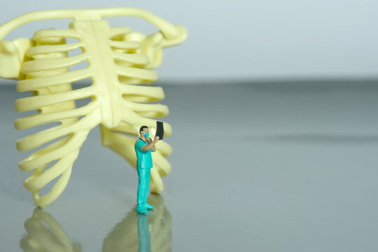 Miniature people toy figure photography. A doctor nurse observing on x ray result scan film in front of rib bone skeleton