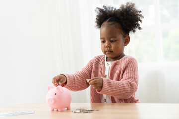 Girl kid putting money into the piggybank. African American girl kid inserting a coin in a piggy...