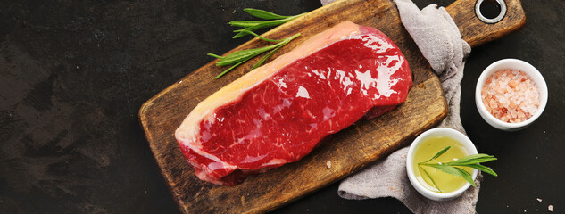 Raw striploin beef steak dark background.