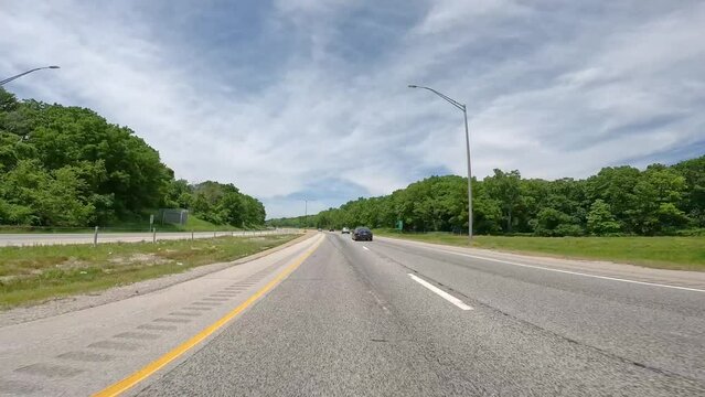 POV driving on Interstate 280 around the south side of the Quad Cities of Illinois; divided highway surrounded by trees and follows the Rock River; with little traffic on a sunny day