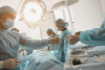 Assistant hands out instruments surgeon during surgery in the operating room