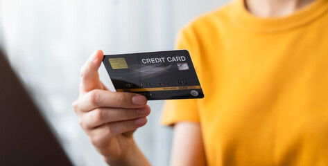 Woman hand holding credit card and using laptop for paying products online via the Internet