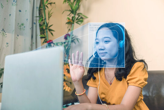 A laptop using facial recognition AI technology to verify an employee's identity for attendance. Automated remote personnel behavior tracking and online monitoring.