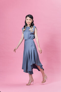 Portrait in full growth the young beautiful woman in a blue dress, isolated on pink background