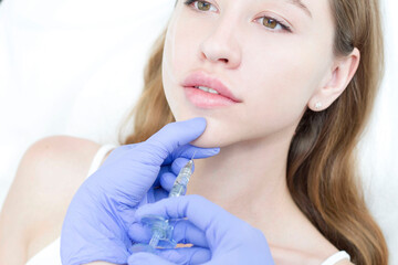 The cosmetologist makes anti-aging injections against wrinkles on the chin, cheeks and neck....