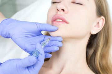 Obraz na płótnie Canvas The cosmetologist makes anti-aging injections against wrinkles on the chin, cheeks and neck. Women's aesthetic cosmetology.