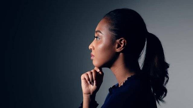 Young African woman thinking in dark room.