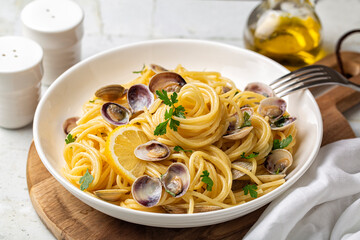 Italian pasta spaghetti with clams and lemon or Spaghetti alle vongole verace, cooked with oil, white wine, garlic, parsley. Selective focus. - obrazy, fototapety, plakaty