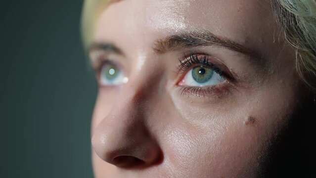 Young Caucasian woman opening eyes in dark room.