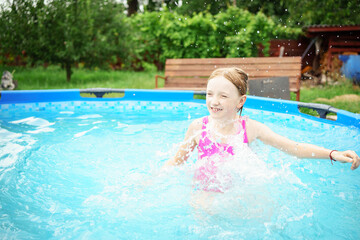 A child in the water. A girl splashes in an inflatable pool in the garden on a sunny summer day. High quality photo