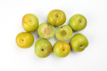 Small mini green fresh juicy plum fruit on white background cut slice half seed many pile