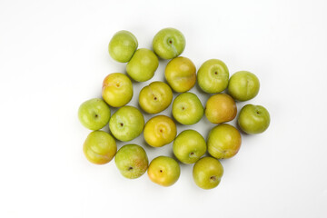 Small mini green fresh juicy plum fruit on white background cut slice half seed many pile