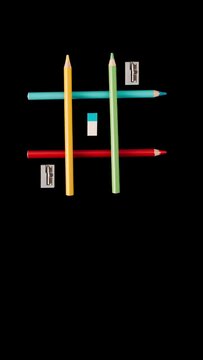 Game Iks Oks, wooden colored pencils, cutter, eraser. , concept of going to school, on black background, video animation for mobil
