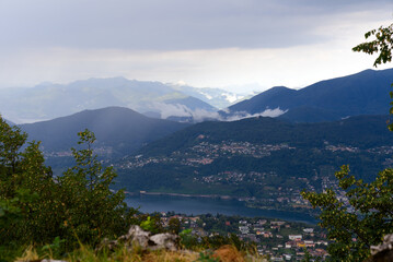 Scenic landscape with mountain panorama and Lake Lugano seen from local mountain San Salvatore at City of Lugano on a cloudy summer day. Photo taken July 4th, 2022, Lugano, Switzerland.