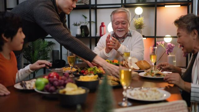 Happy family time,christmas,thanksgiving and relationship.Grandparent is happy to see his child,grandson eating on dining table at home.Asian big family having christmas party eating food together.