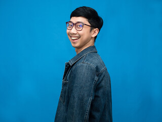 Cheerful man wear glasses jeans shirt turn around to looking with happy smile blue background