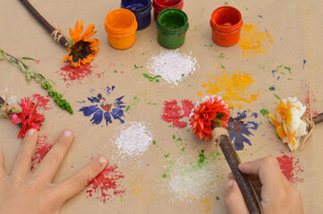Close-up of children's hands that create a drawing using a flower by poking. What to do with...