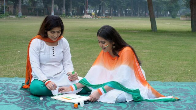 A teenage school student drawing Indian National Flag and posing for a camera. A pretty lady and her young daughter celebrating Republic Day together - patriotism  patriotic  National holiday  fest...
