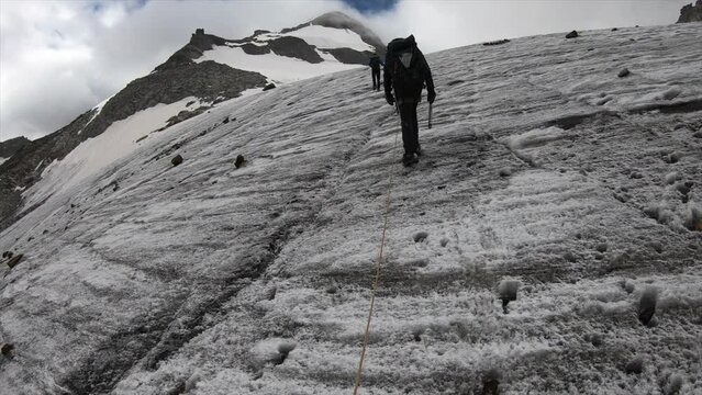 A crystal seeker, alpinist in the Swiss alps, hikes a mountain on a glacier with all his equipement, Helmet