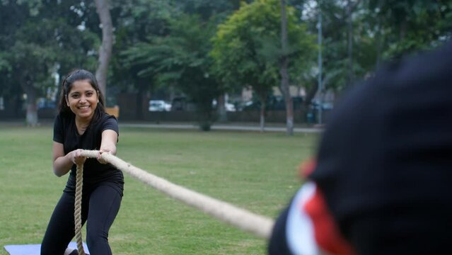 A young Indian girl playing a tug of war game in the park - outdoor sport  physical strength . Two friends playing an outdoor sport together - leisure time  a fun game  strength and stamina