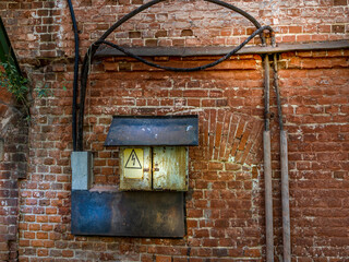 Old electrical wiring on a brick wall. Retro style. Vintage background with wires and electric shield.