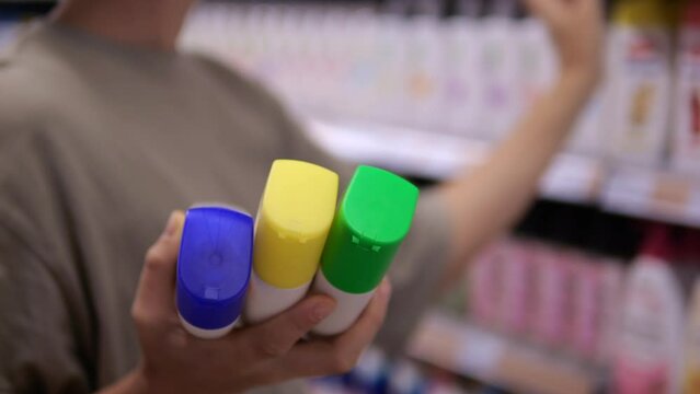 A Woman Chooses A Hair Shampoo Chooses From Different Types Of The Same Brand, For Different Types Of Hair. The Customer Chooses The Best Hair Care Product In The Specialized Store.