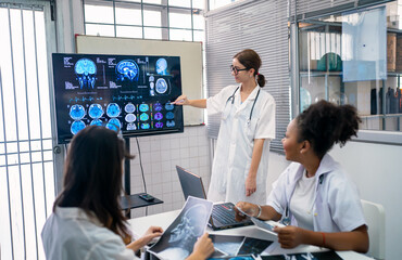 Team of doctors discuss results of X-Ray or MRI scan of patient's brain in medicine office of clinic