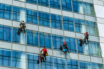 Industrial climbers cleaning windows on the facade of an office building.