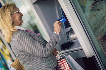 Senior woman using ATM machine with credit card
