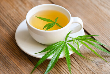 Cannabis tea herbal on tea cup with cannabis leaf marijuana leaves herb on wooden background,...