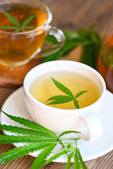 Cannabis tea herbal on tea cup with cannabis leaf marijuana leaves herb on wooden background, health tea with hemp leaf plant THC CBD herbs food and medical concept