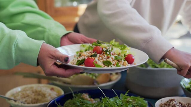 Fresh vegan salad being served on a plate at a group meal.