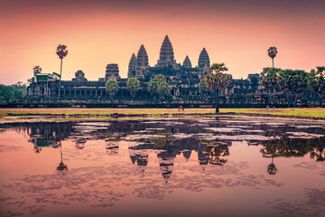 Fototapeta premium Colorful dawn in Angkor Wat, iconic buddhist temple sprawling complex building surrounded by a wide moat and features intricate carvings. Spectacular summer scene of Krong Siem Reap, Cambodia, Asia.