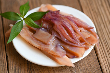 pickled squid on white plate, raw squid for cooking food on wooden background, preserving food seafood