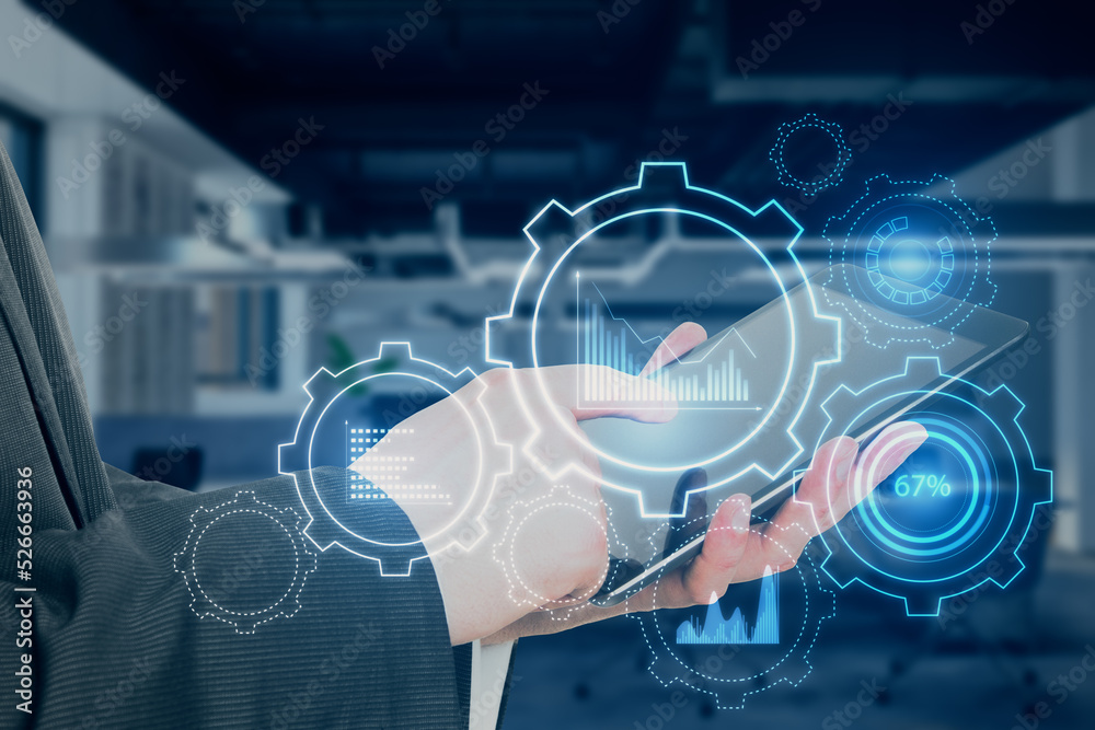 Poster close up of businessman hand pointing at tablet with glowing cogwheel and chart hologram on blurry o