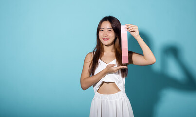 Portrait of happy female hold color card under sun protection, skin beauty face, Asian beautiful young woman smiling and holding skin color scale paper studio shot isolated on blue background