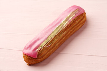 Eclair dessert with icing on pink wooden background