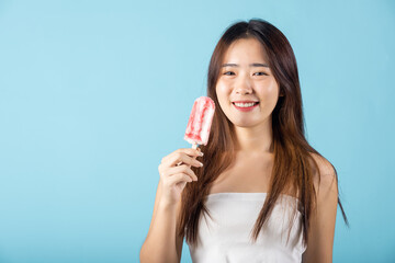 Portrait of happy Asian young beautiful woman holding delicious ice cream wood stick mixed fruit flavor, studio shot isolated on blue background, sweet tasty frozen dessert on summer time