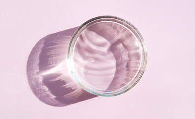 Micellar water serum texture in petri dishes on light pink background cosmetic research concept	
