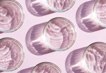 petri dish with liquid water on plain pink background water ripple texture	
