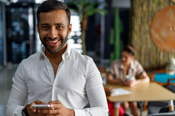 Smiling businessman using smartphone in office