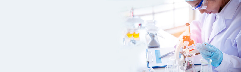 Banner Asian woman scientist hand write note research in medical lab look at science microscope....