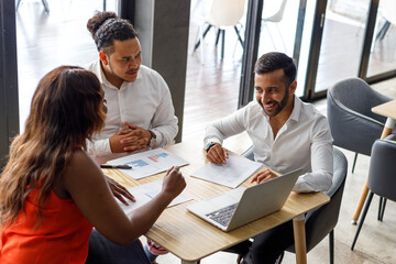Multiracial colleagues analyzing reports at desk in office