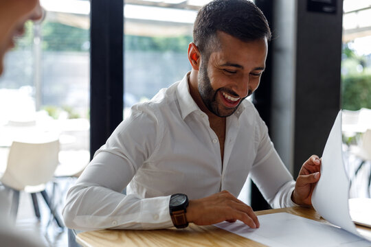 Happy businessman analyzing report on desk in office