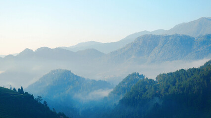 Dramatic sunset over mountain landscape. Beautiful landscape foggy hills twilight time. Blue golden...