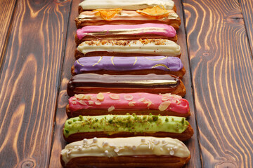 Assortment of sweet and colorful eclairs on wooden background