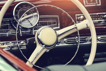 Interior of a retro old-fashioned car with steering wheel and dashboard