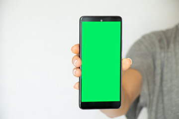 A girl on a white background in her hand holds a mobile phone with a green screen, a template with a phone, a green screen