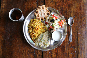 A full vegetarian dinner in metal dishes on a wooden table. View from above.